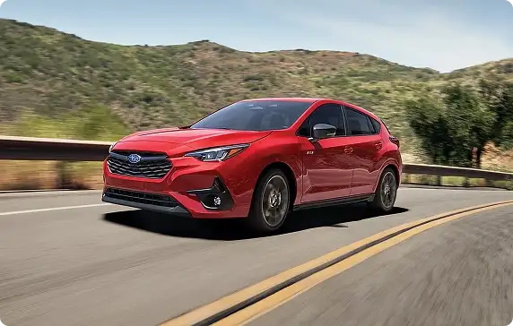 Red 2026 Subaru Impreza driving on a mountain road