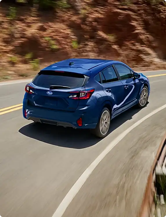 Rear view of a blue 2026 Subaru Impreza on a canyon road