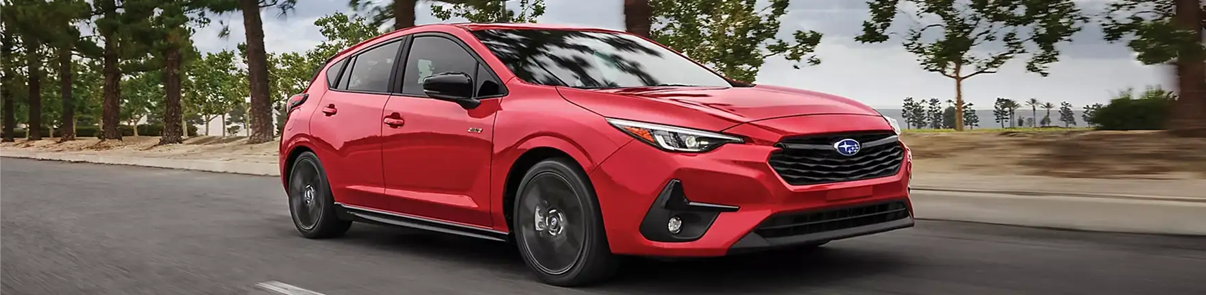 Red 2026 Subaru Impreza RS driving past a modern building