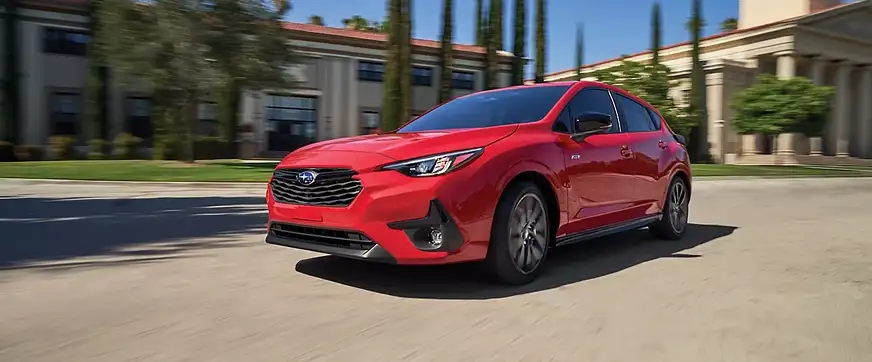Red 2026 Subaru Impreza RS driving past a modern plaza