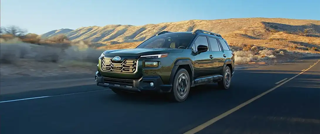 2026 Subaru Outback driving an open road through the mountains