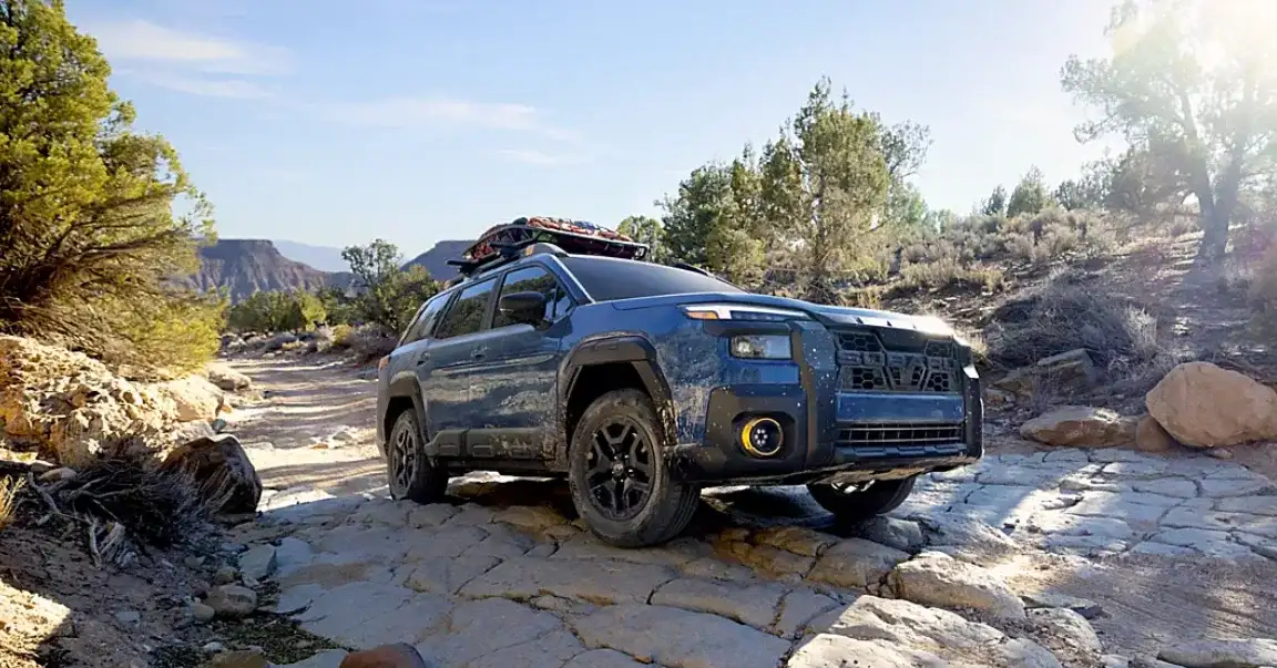 A blue 2026 Subaru Outback navigating a rocky terrain