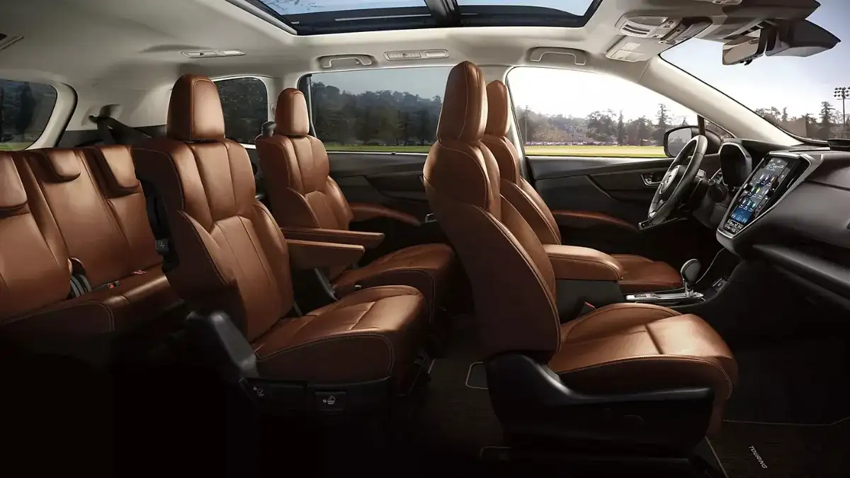 2026 Subaru Ascent interior in Java Brown Nappa leather, showing second-row captain's chairs, walk-through aisle to the third row, and the 11.6-inch portrait touchscreen