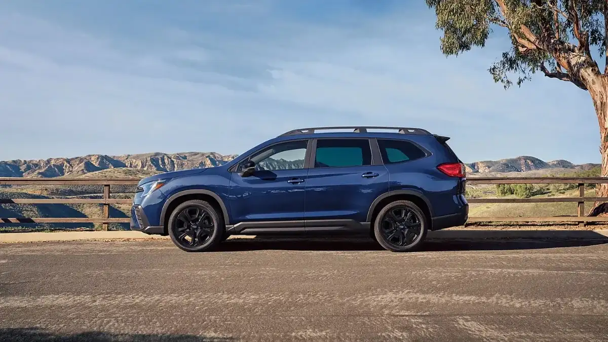2026 Subaru Ascent Onyx Edition Touring in Sapphire Blue Pearl, side profile showing 20-inch black-finish alloy wheels and blacked-out exterior accents against a desert mountain backdrop