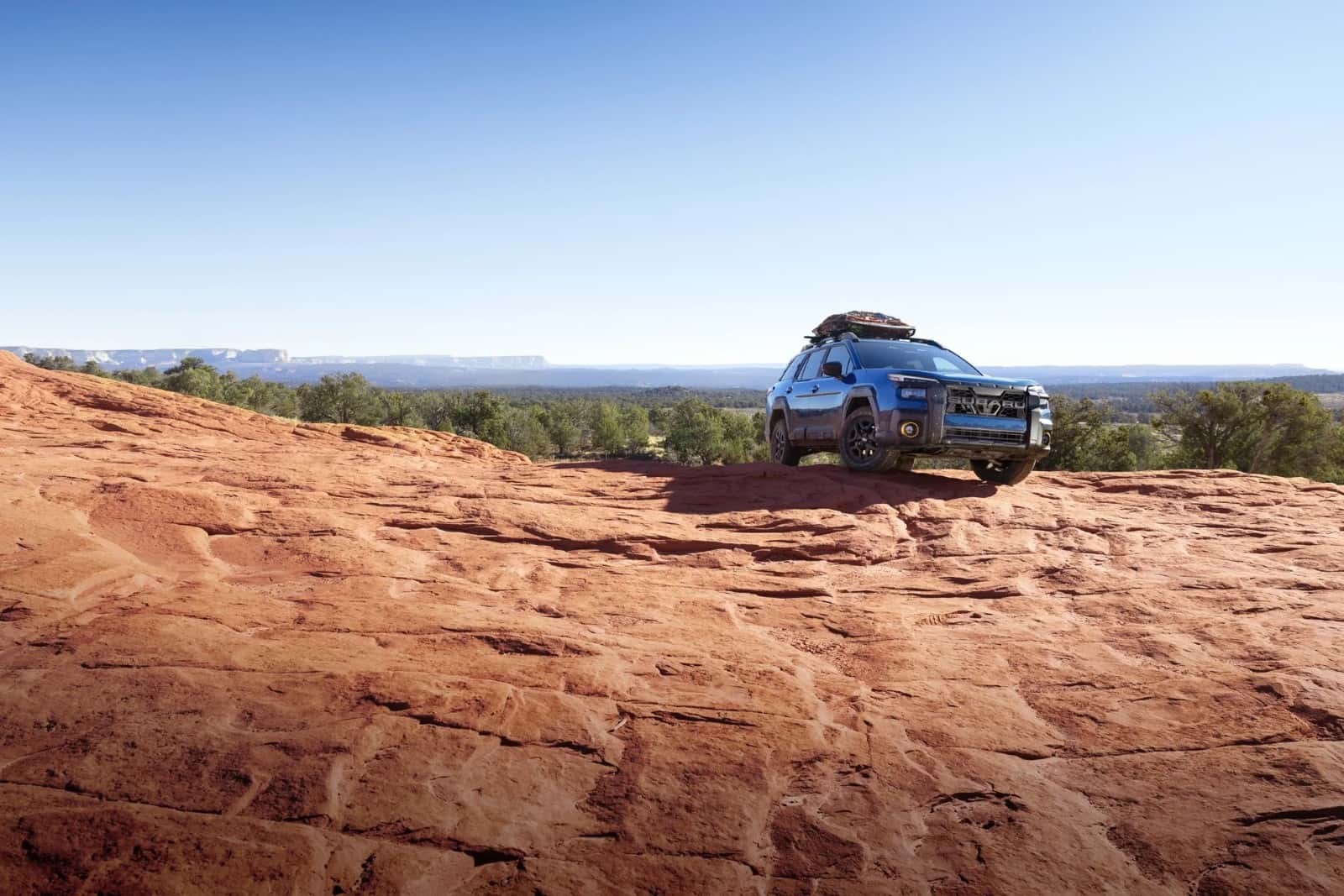 A blue 2026 Subaru Outback Wilderness on red-rock desert terrain in the Southwest — the heat and high-load conditions that test the Lineartronic CVT