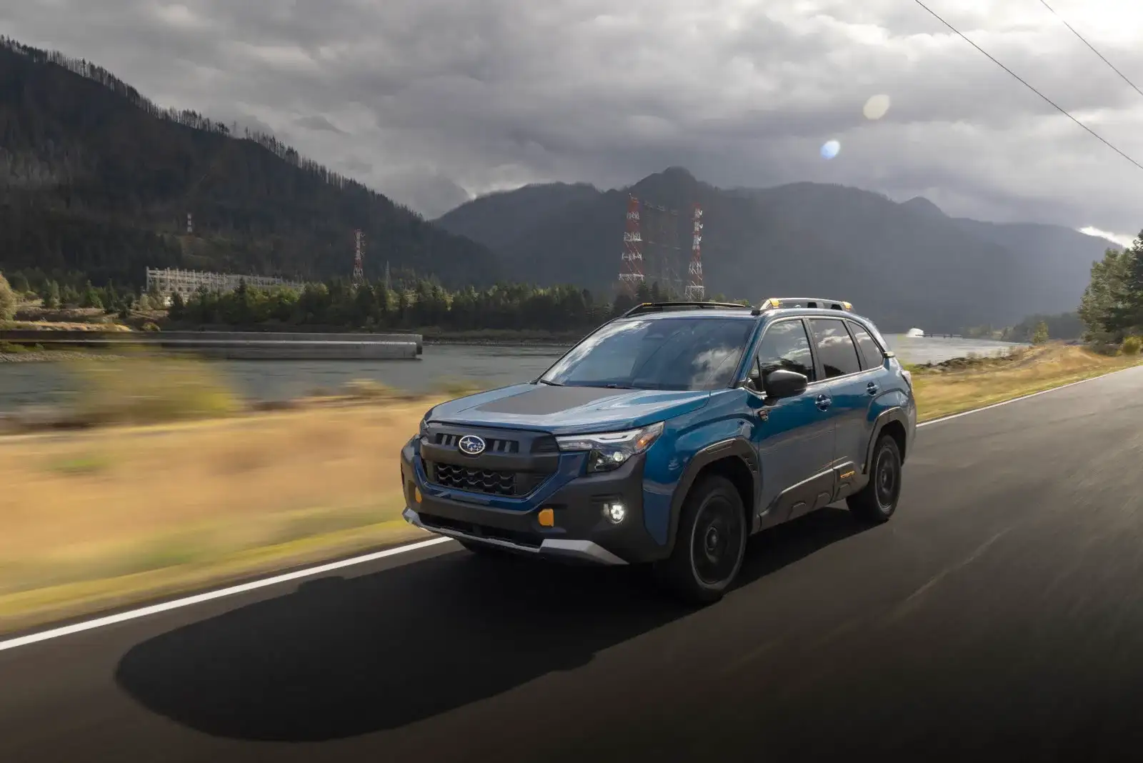 A 2026 Subaru Forester Wilderness driving a mountain highway under a dramatic sky