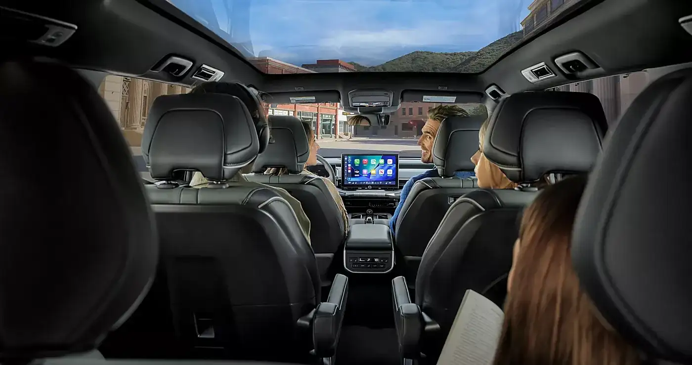 View from the third row of the Getaway cabin — a family seated across three rows with the center touchscreen.