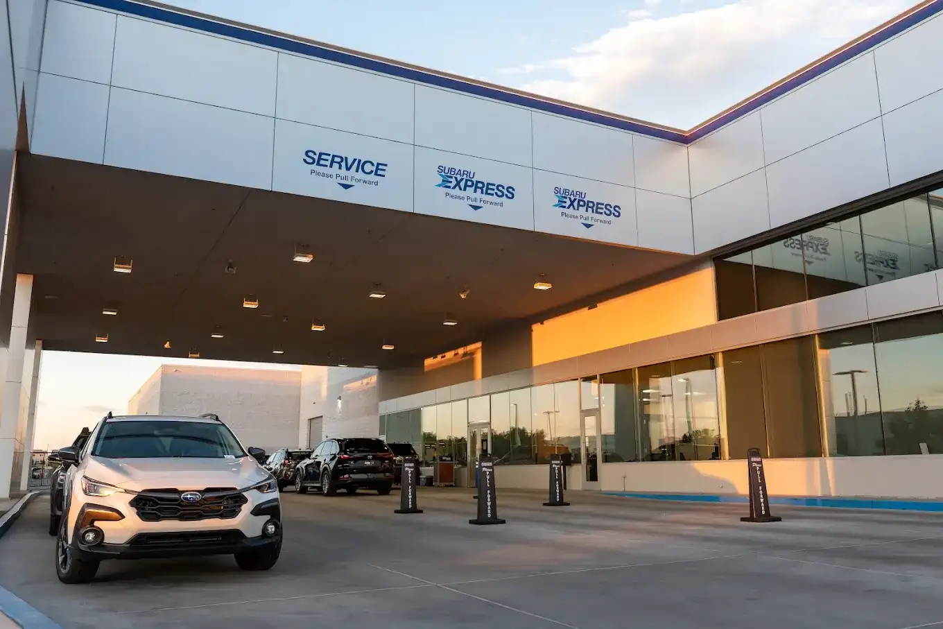 The Subaru Express service drive at Findlay Subaru of Las Vegas at dusk, with vehicles pulled forward under the SERVICE and SUBARU EXPRESS canopy