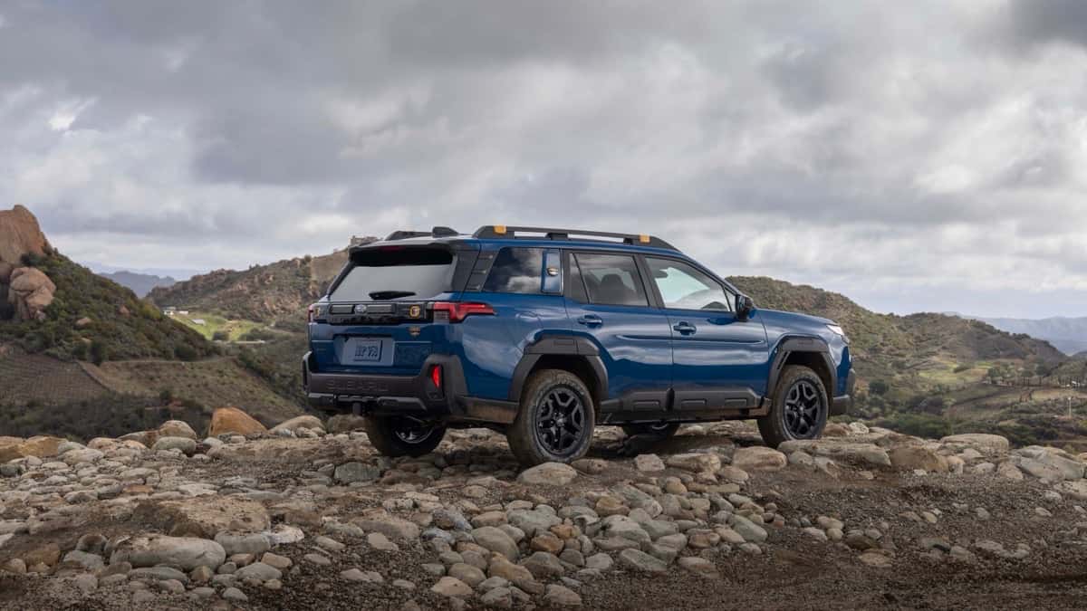 A blue Subaru Forester Wilderness parked on a rocky desert overlook, rear three-quarter view