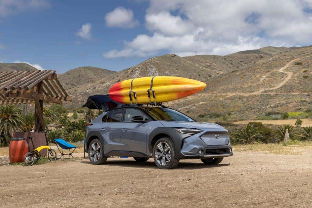The Strong 2023 Subaru Solterra On The Beachsie, With A Surfing Board Hooked On Top