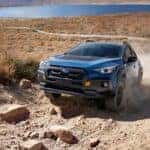 The Stunning 2024 Subaru Crosstrek Wilderness Driving Up A Sandy Grassland Path