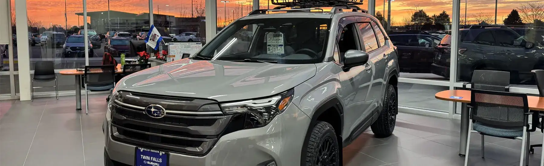 A River Rock Pearl 2025 Subaru Forester Premium in the Twin Falls Subaru Showroom, with a brilliant sunrise behind it.