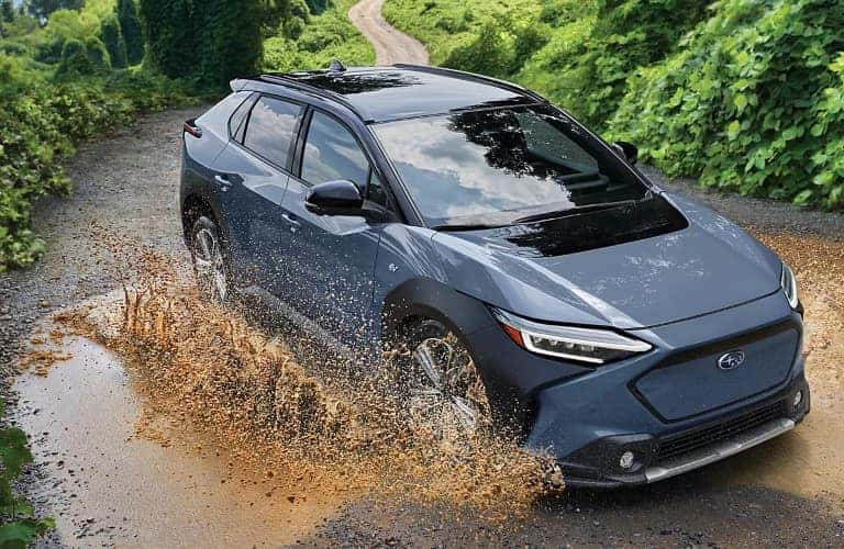 Blue 2023 Subaru Solterra EV Driving Through Mud