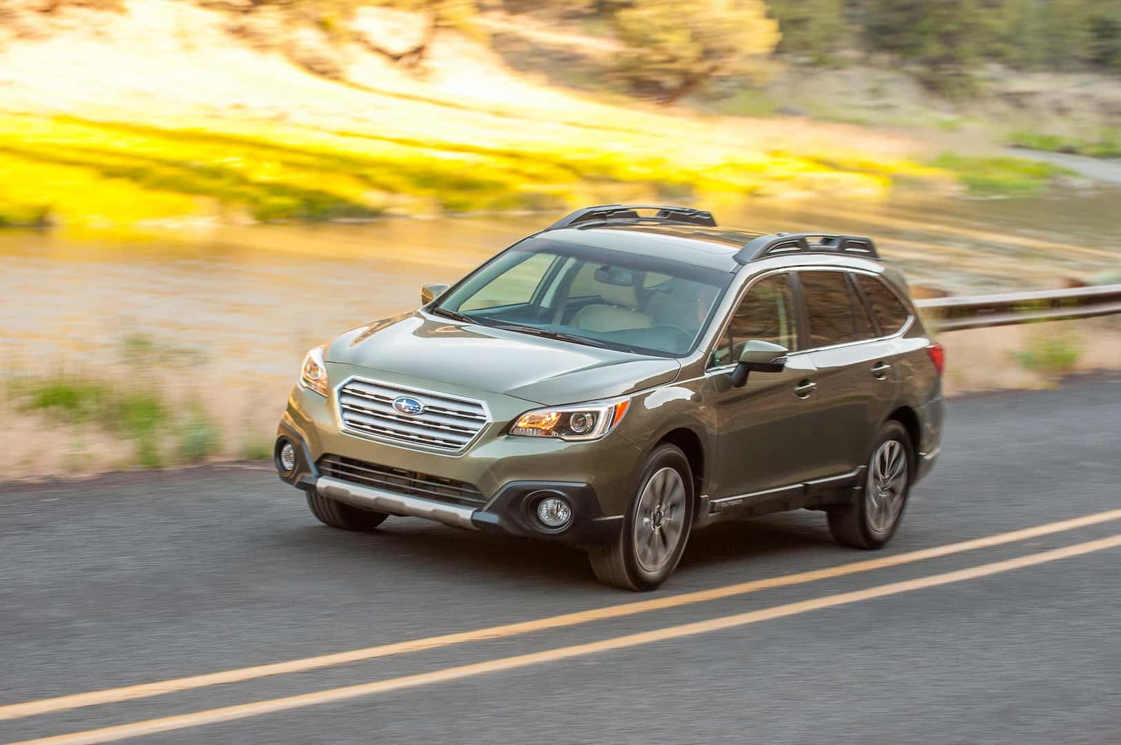 2015 Subaru Outback driving down a rural road.