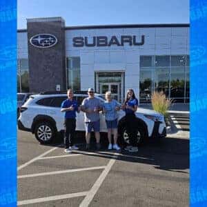 Patti & Tim, from Hansen, Idaho, with their Crystal White Pearl 2024 Subaru Outback Premium with Product Specialist Cory Budden in front of Twin Falls Subaru