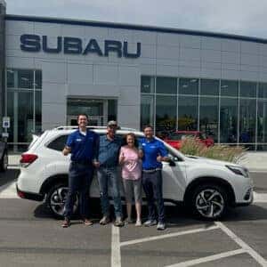 Travis & Gaye from Spring Creek, Nevada, with their Crystal White Pearl 2024 Subaru Forester Touring in front of Twin Falls Subaru, with Purchase Advisor Kaden Barrus.