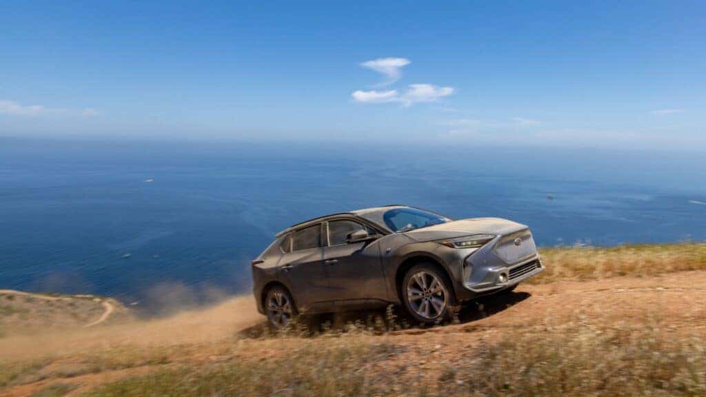 An Adventurous 2023 Subaru Solterra Driving Up A Hill Epically