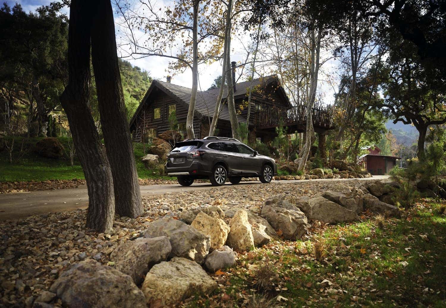 Rear Side View of the Subaru Outback Parked at the Mountain Cabin in the Woods