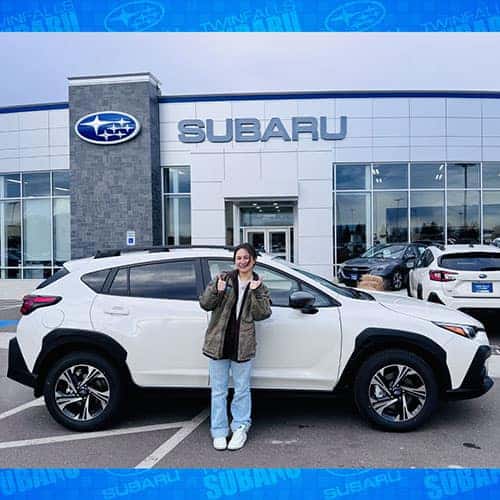Emily, from Jerome, Idaho, with her Crystal White Pearl 2024 Subaru Crosstrek Premium in front of the Magic Valley's #1 Volume Automotive Retailer (MVN1VAR) Twin Falls Subaru in Twin Falls, Idaho