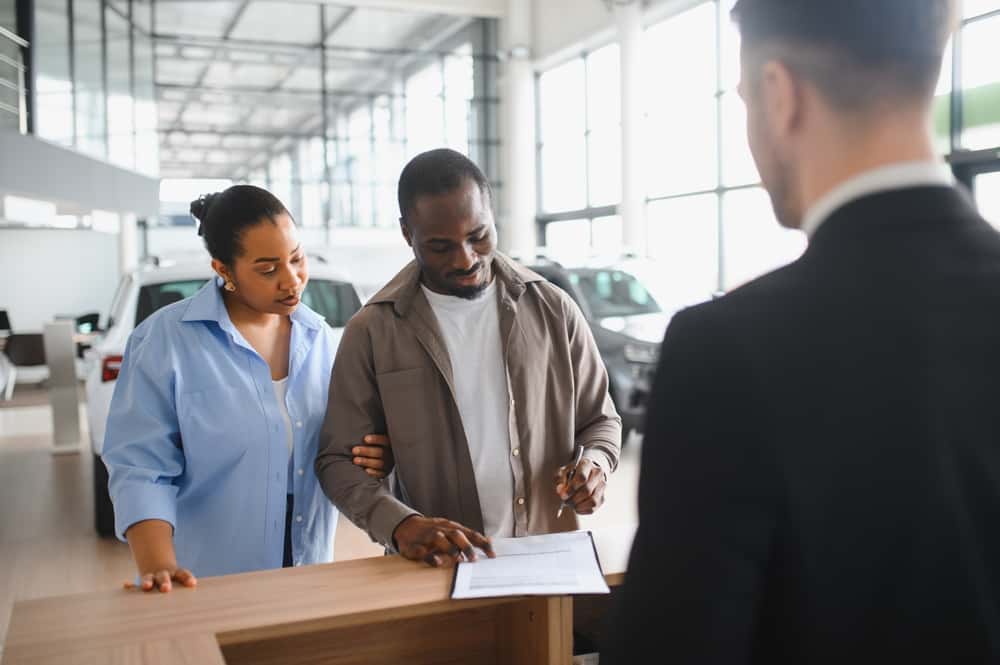African,American,Couple,Signing,Contract,For,New,Car,Purchase,At