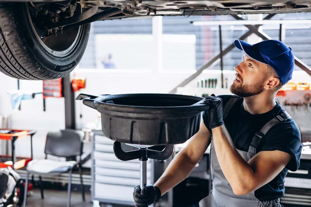 A mechanic draining oil during an oil change