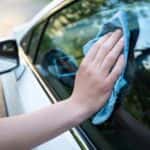 Male hand holding a blue cloth cleaning a car window