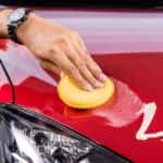 Man's hand waxing the hood of a car