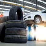 New tires in foreground with a car on a jack in the background