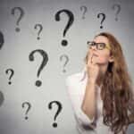 Thinking woman with glasses surrounded by question marks