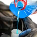 Woman pouring blue antifreeze into a car