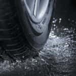 Car tire splashing water on pavement