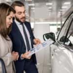 Young woman listening to a car salesman
