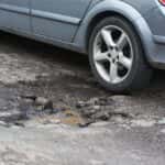 car tire hitting a pothole on a street