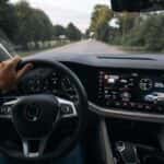 Man driving modern new SUV with hand on steering wheel