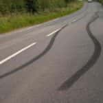 Skid marks on black pavement along a country road