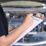 Young woman with a clipboard inspecting a car