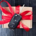 Wooden box wrapped in red ribbon with car starter on top