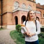 Young woman standing in front of college building