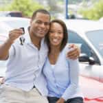 Smiling couple at the lot holding a used vehicle key