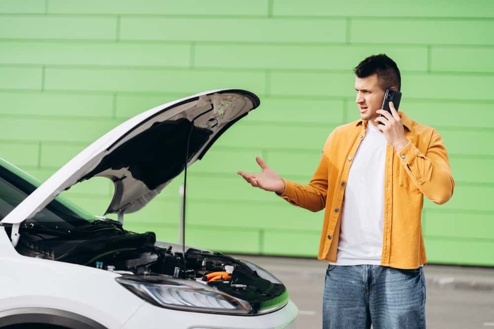 Man next to vehicle on phone with the Collision Center