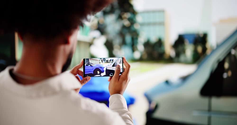 Man taking pictures of vehicle after a collision