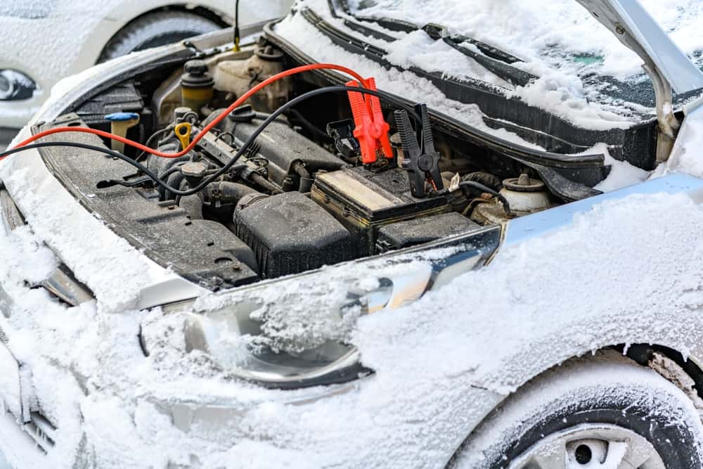 Charging a car in the snow during winter car maintenance 