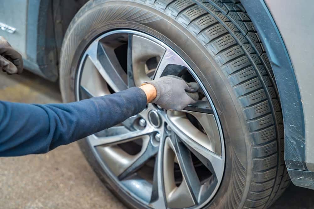 Mechanic closing tire valve during winter car maintenance