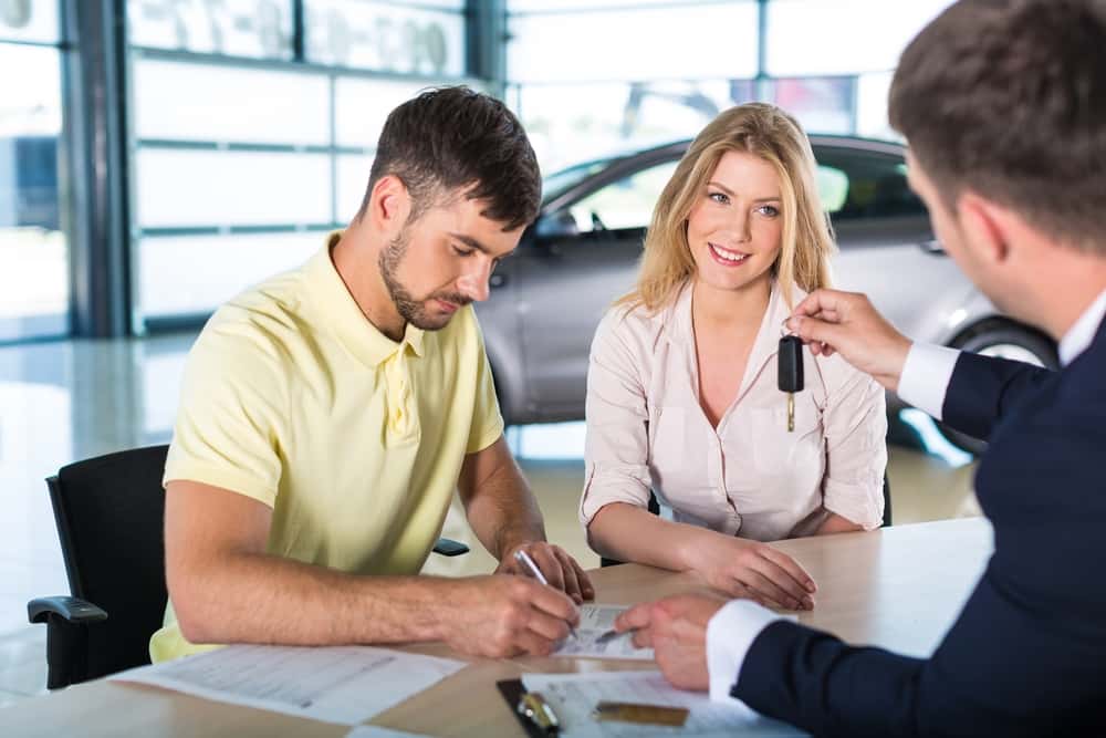 A couple getting the keys to a vehicle at a dealership