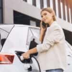 A young woman standing by her EV at an EV charging station