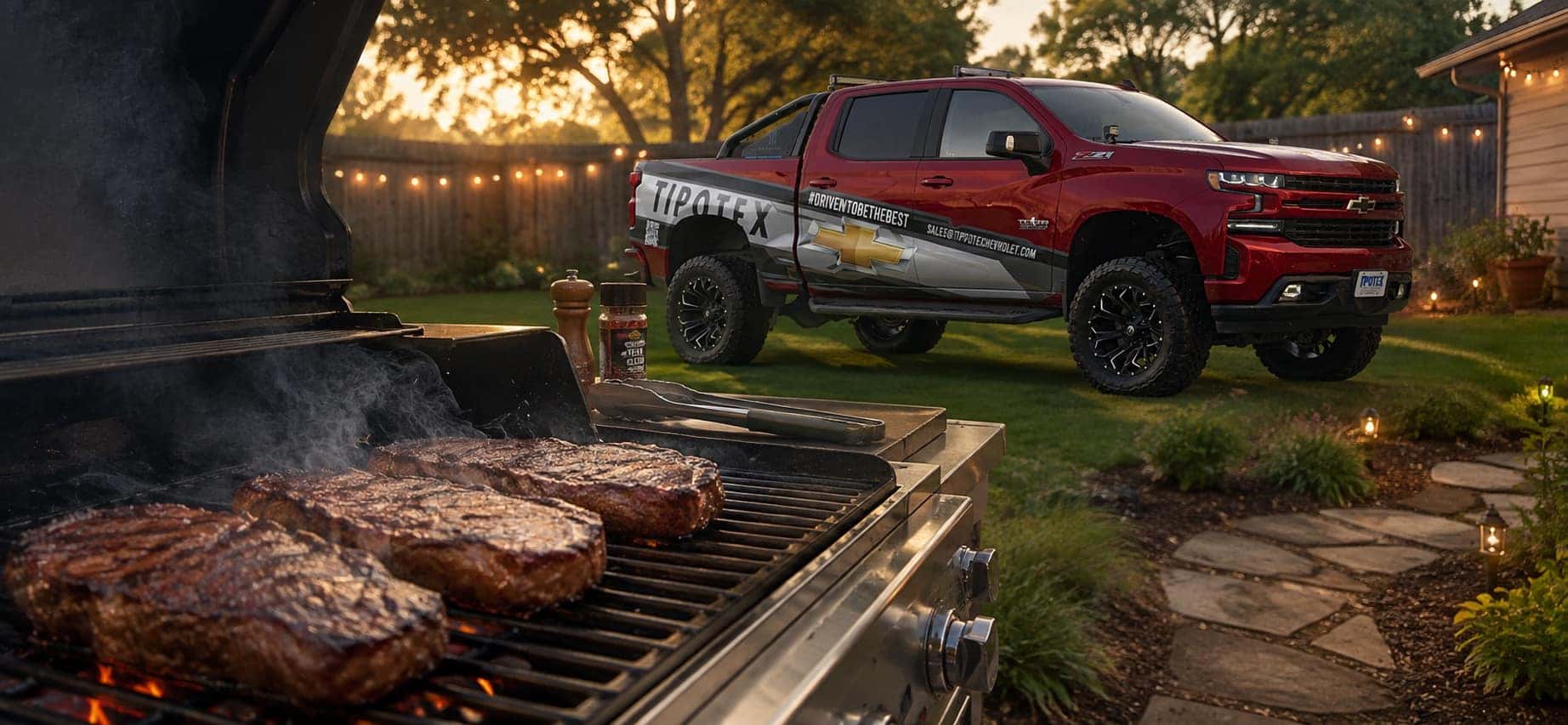 Grill with steaks on top with truck in background