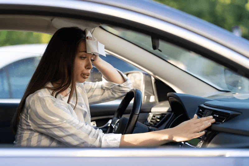 Woman in her car sweating from a hot summer day. 