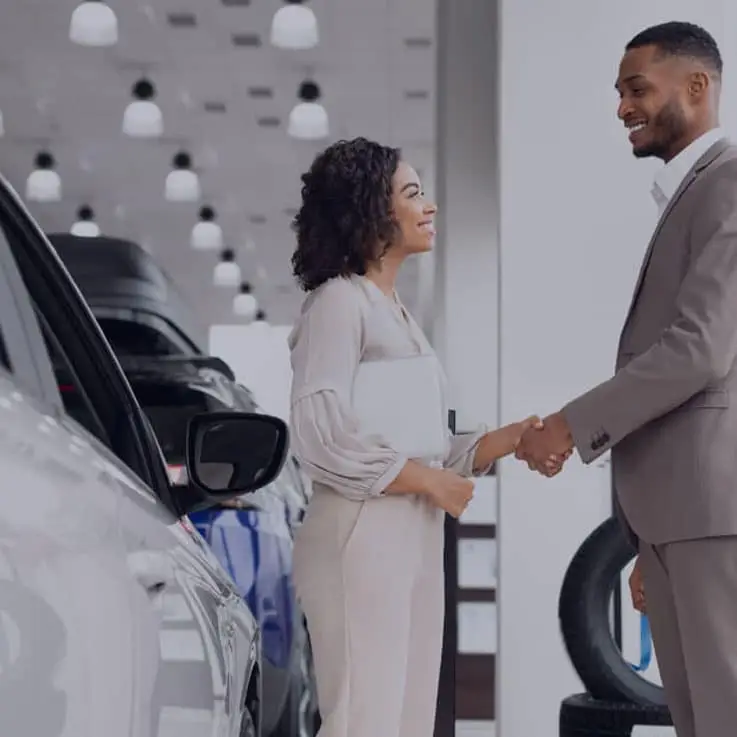 Woman and man standing next to a car in a showroom