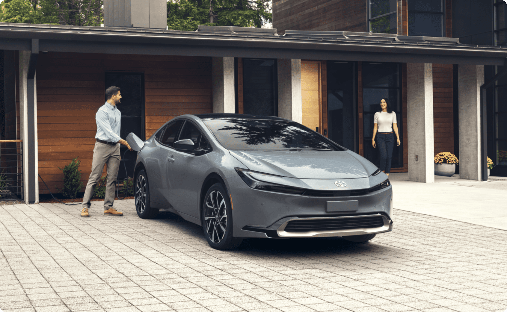 Couple leaving house and husband unplugging Toyota Prius Plug-In Hybrid