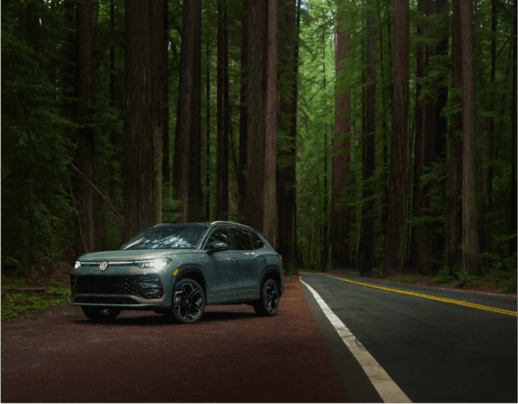 2026 Volkswagen Tiguan SEL R-Line Turbo 4MOTION in Avocado Green driving through a forest road